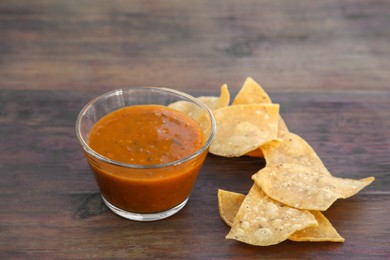 Tasty salsa sauce and Mexican nacho chips on wooden table, closeup