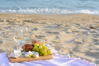 Photo of Glasses with white wine and snacks on sandy seashore. Space for text