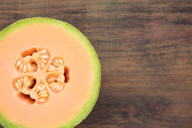 Photo of Half of fresh ripe melon on wooden table, top view. Space for text