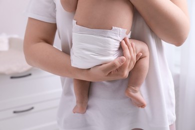 Mom holding her baby in diaper at home, closeup