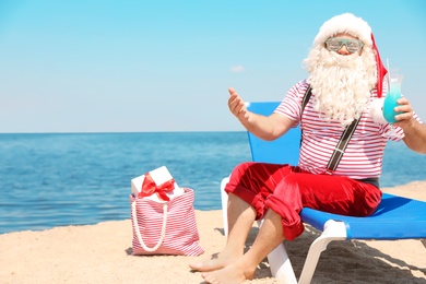 Photo of Authentic Santa Claus with cocktail resting on lounge chair at resort