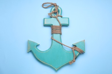 Photo of Wooden anchor with hemp rope on pale blue background, top view
