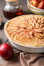 Photo of Tasty apple pie in baking dish on grey table, closeup