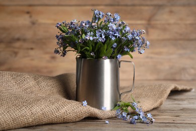 Photo of Beautiful forget-me-not flowers on wooden table, closeup