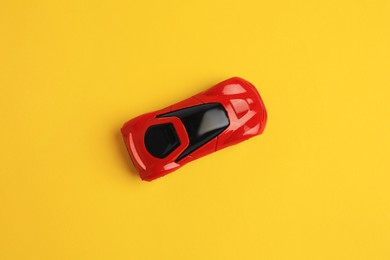 Photo of One red car on yellow background, top view. Children`s toy