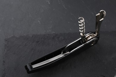 Photo of One corkscrew (sommelier knife) on grey textured table, closeup