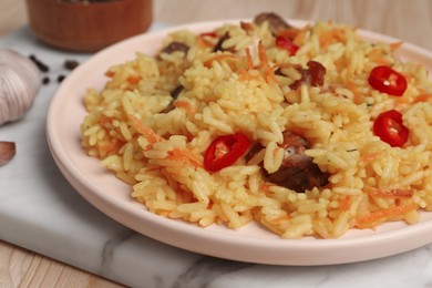 Photo of Delicious pilaf with meat on wooden table, closeup