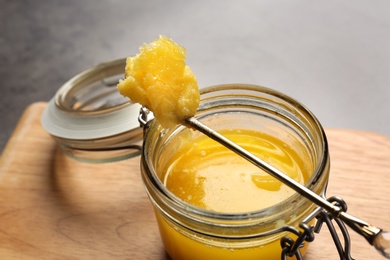 Photo of Jar and spoon with clarified butter on wooden board