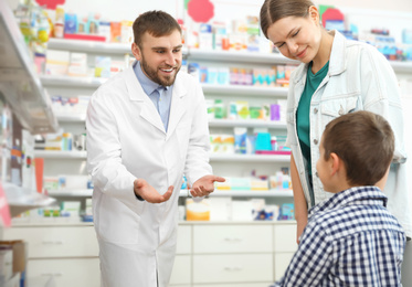 Image of Professional pharmacist working with customer in modern drugstore