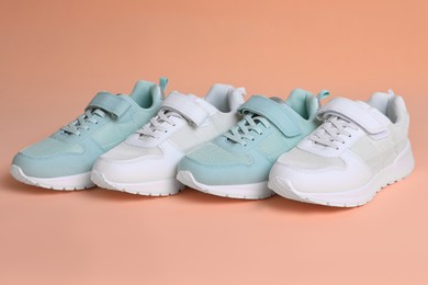Photo of Different stylish sports shoes on pale coral background