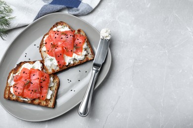 Photo of Delicious sandwiches with cream cheese, salmon and black sesame seeds served on light grey table, flat lay. Space for text