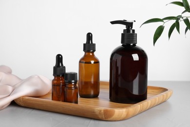 Photo of Different cosmetic products and leaves on grey table