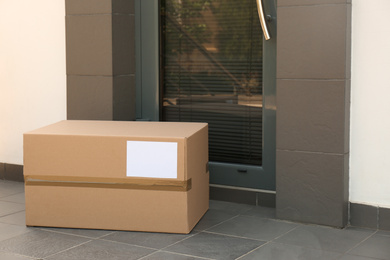 Photo of Cardboard box on floor near door. Parcel delivery service