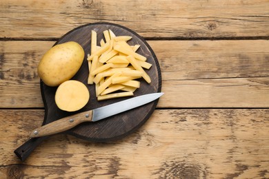 Photo of Potatoes and knife on wooden table, top view with space for text. Cooking delicious french fries