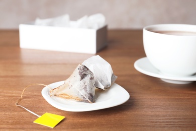 Photo of Saucer with pyramid teabags on wooden table