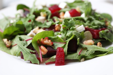 Photo of Delicious beet salad with arugula and walnuts on plate, closeup view