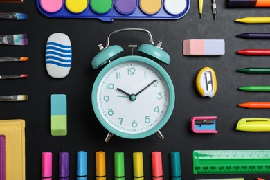 Photo of Flat lay composition with alarm clock and different stationery on blackboard. School time