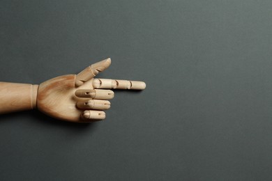 Photo of Wooden mannequin hand on grey background, top view. Space for text