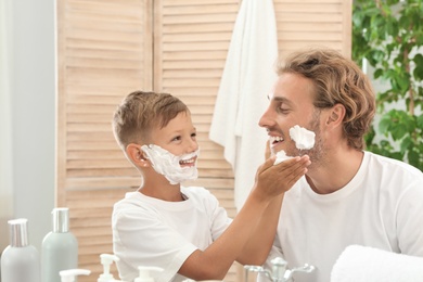 Photo of Father and son applying shaving foam in bathroom