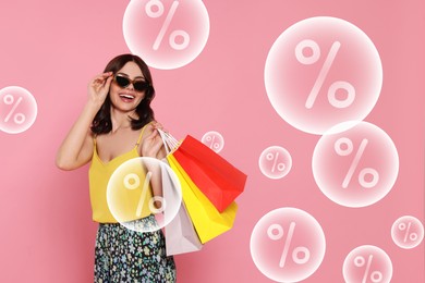 Image of Discount offer. Happy woman with paper shopping bags on pink background. Bubbles with percent signs flying near her