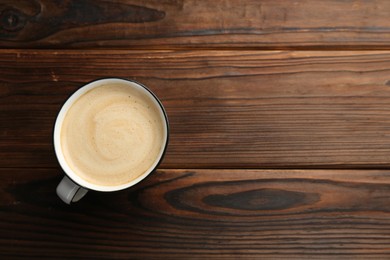 Photo of Tasty cappuccino in cup on wooden table, top view. Space for text
