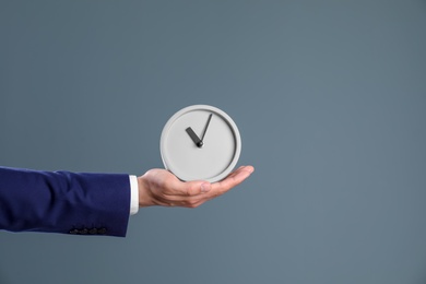 Photo of Young businessman holding clock on color background. Time management