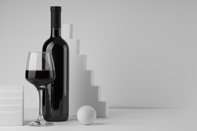 Photo of Stylish presentation of delicious red wine in bottle and glass on white background. Space for text