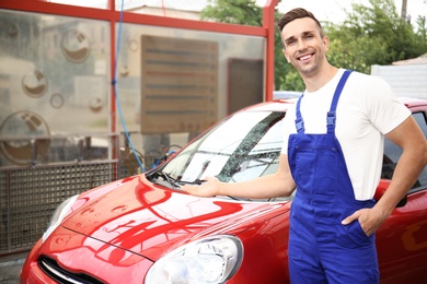 Photo of Male worker standing near clean vehicle at car wash