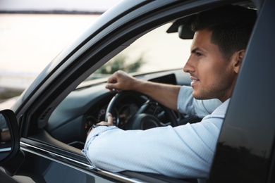 Photo of Handsome man driving his modern car, view from outside