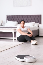 Photo of Scales and overweight woman in sportswear on background