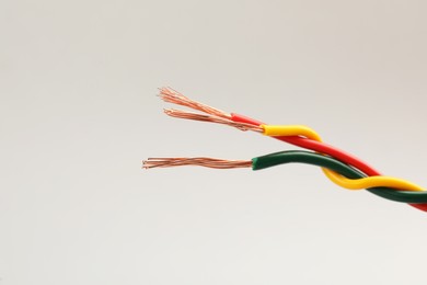 Photo of Three twisted electrical wires on light background, closeup