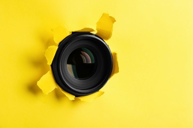 Photo of Hidden camera lens through torn in yellow paper