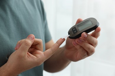Photo of Diabetes test. Man checking blood sugar level with glucometer at home, closeup