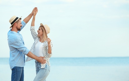 Photo of Happy romantic couple dancing on beach, space for text
