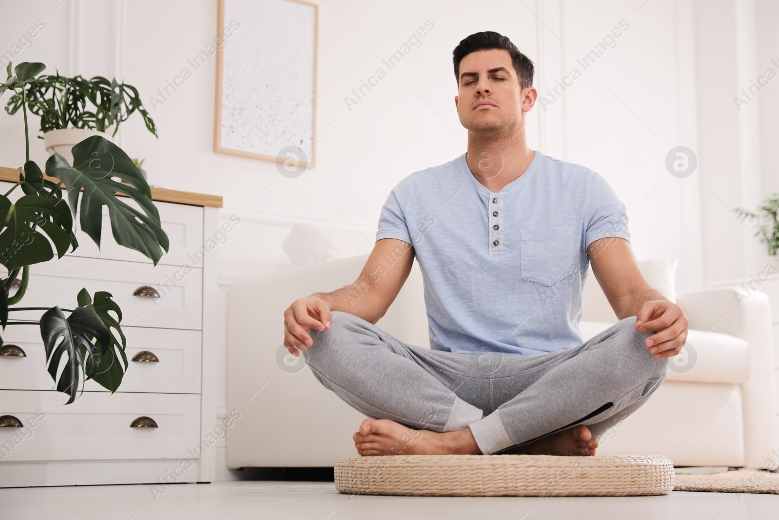 Photo of Man meditating on wicker mat at home