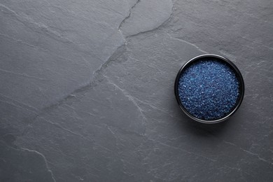 Photo of Bowl of blue food coloring on grey table, top view. Space for text