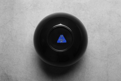 Photo of Magic eight ball with prediction So It Shall Be on grey table, above view