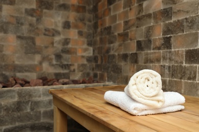 Photo of White towels on wooden bench in salt sauna. Space for text