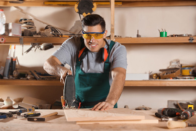 Photo of Professional carpenter working with jigsaw at workbench