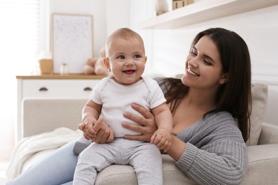 Photo of Happy young mother with her cute baby in living room