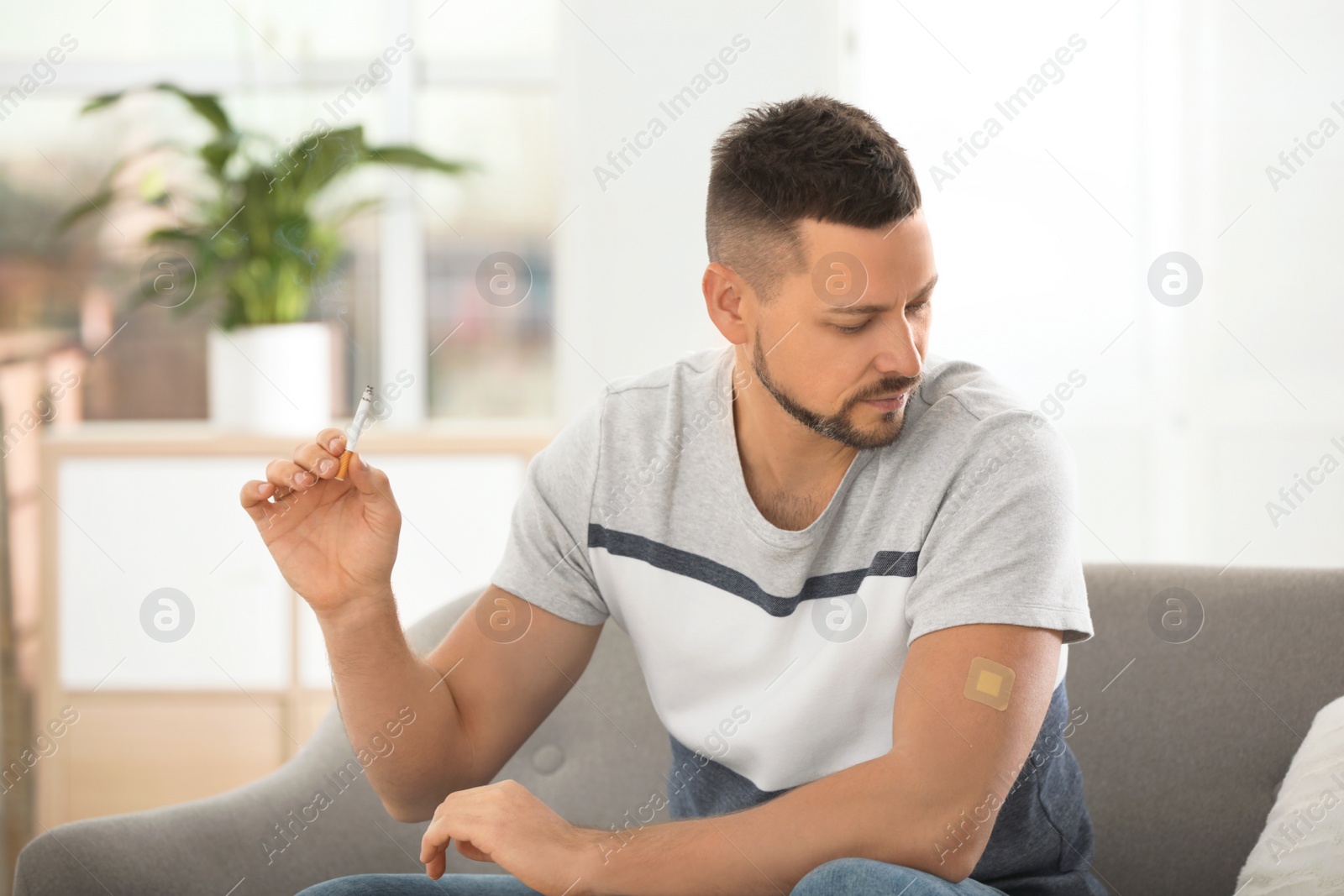 Photo of Man with nicotine patch and cigarette at home