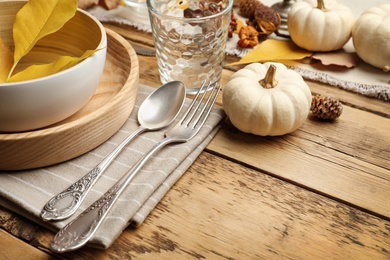Photo of Seasonal table setting with pumpkins and other autumn decor on wooden background, closeup. Space for text