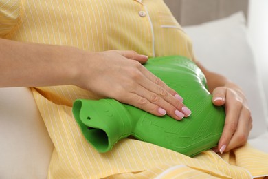 Photo of Woman using hot water bottle to relieve menstrual pain on bed at home, closeup