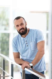 Photo of Portrait of handsome mature man leaning on handrail indoors