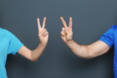 Photo of Man and woman showing victory gestures on color background