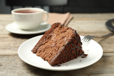 Photo of Piece of delicious chocolate truffle cake and fork on wooden table, closeup