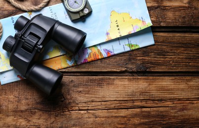 Photo of Modern binoculars, map, compass and rope on wooden table, flat lay. Space for text