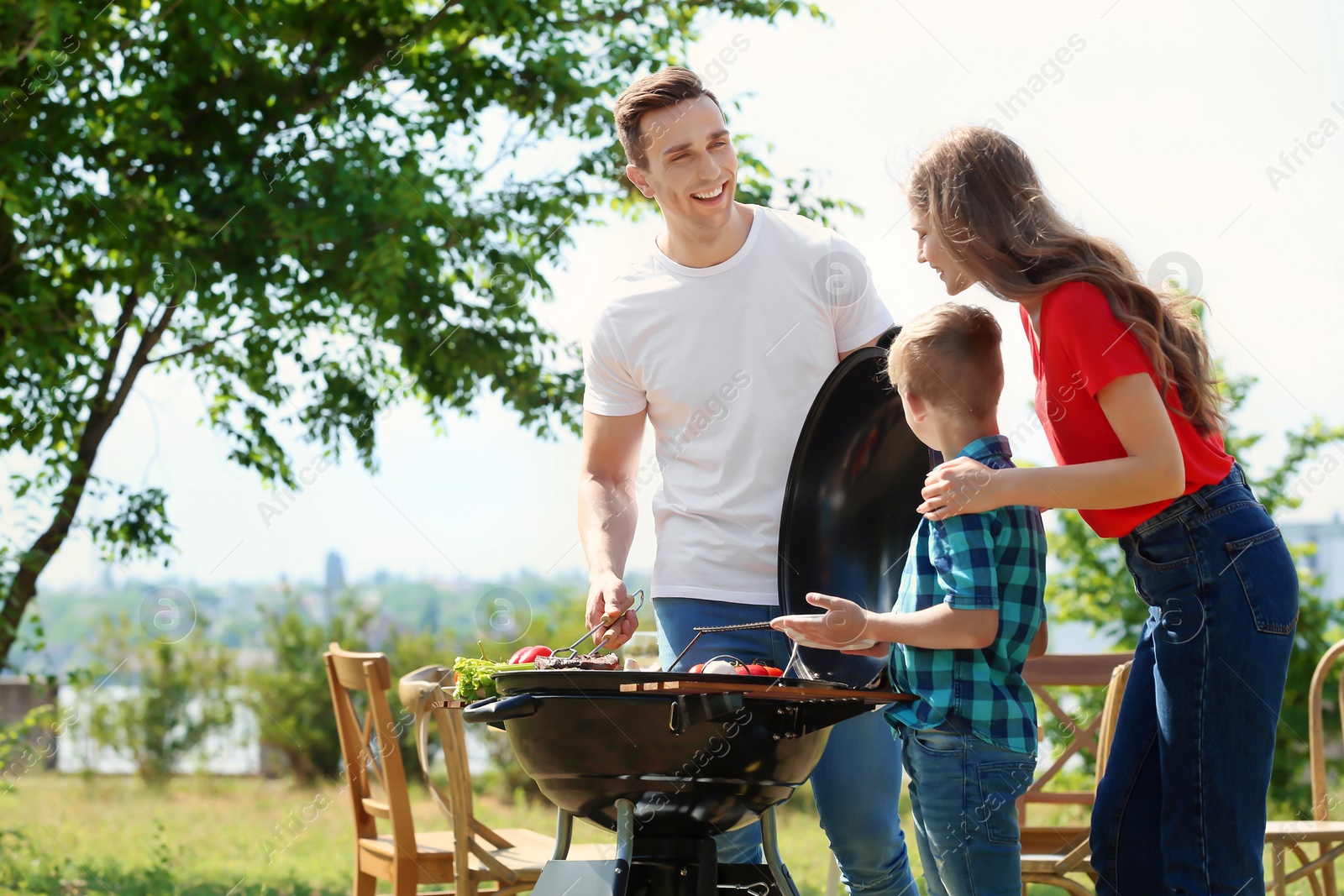 Photo of Happy family having barbecue with modern grill outdoors