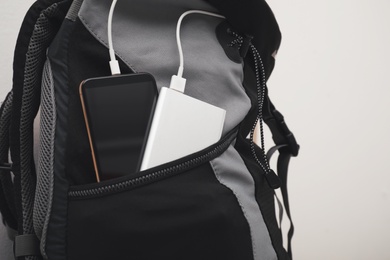 Photo of Smartphone charging with power bank in backpack, closeup