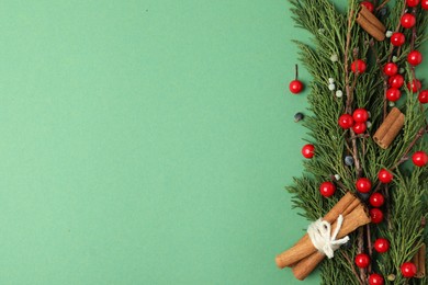 Photo of Christmas flat lay composition with conifer branches and berries on green background, space for text. Winter holidays